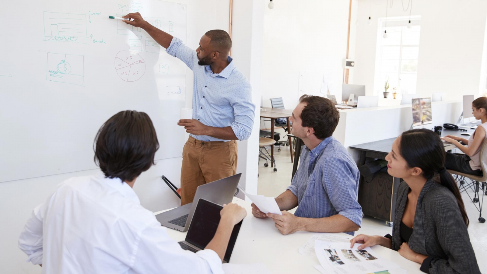 People meeting and drawing on a white board